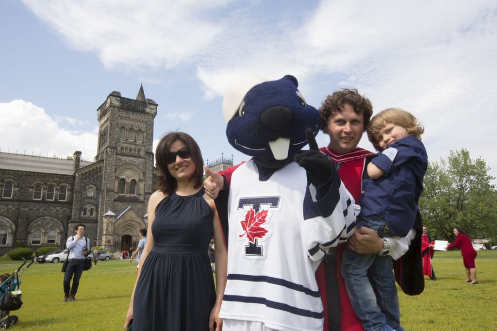 New graduate with True Blue mascot and family